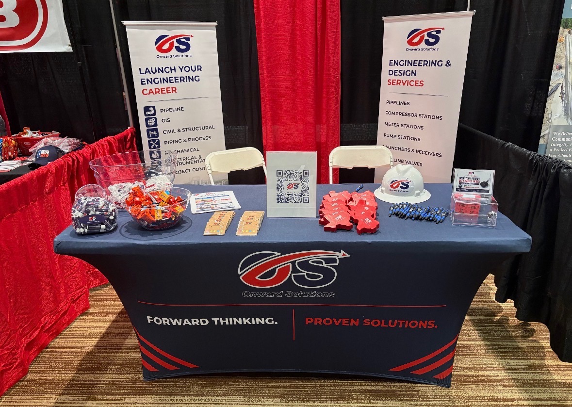 Onward Solutions trade show booth with navy branded tablecloth, roll-up banners, white hard hat, branded pens, and koozies