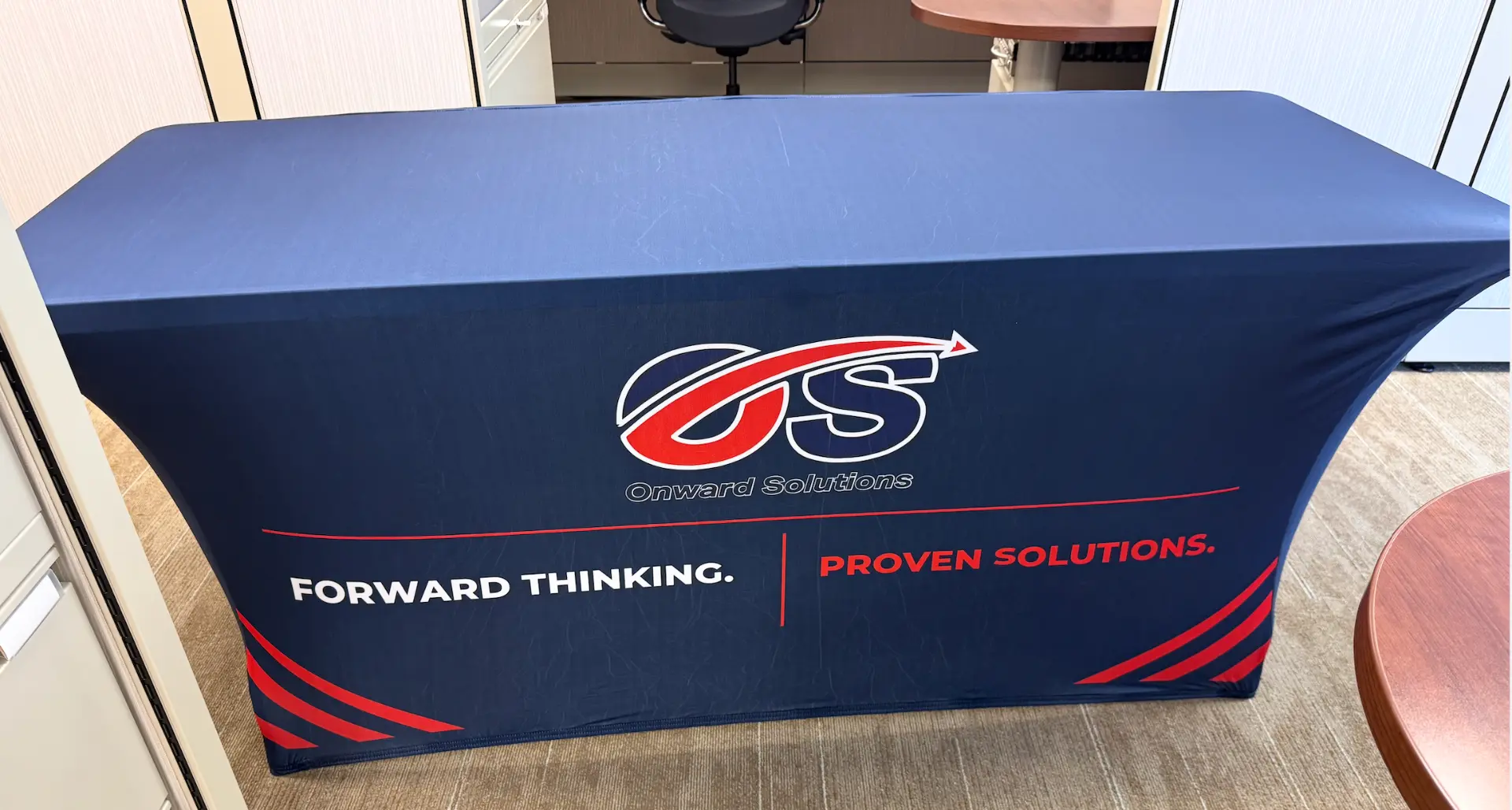 Navy fitted tablecloth with the Onward Solutions OS logo, Forward Thinking. Proven Solutions. tagline, and red corner stripes